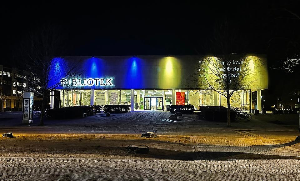 Växjö stadsbibliotek lyser i gult och blått. 