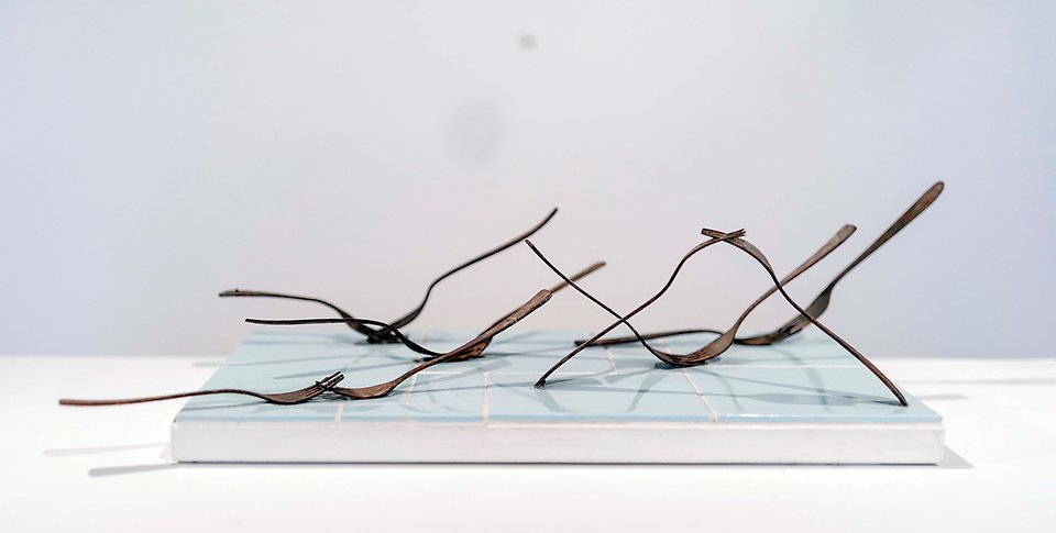 En installation bestående av gafflar på en kakelplatta. 